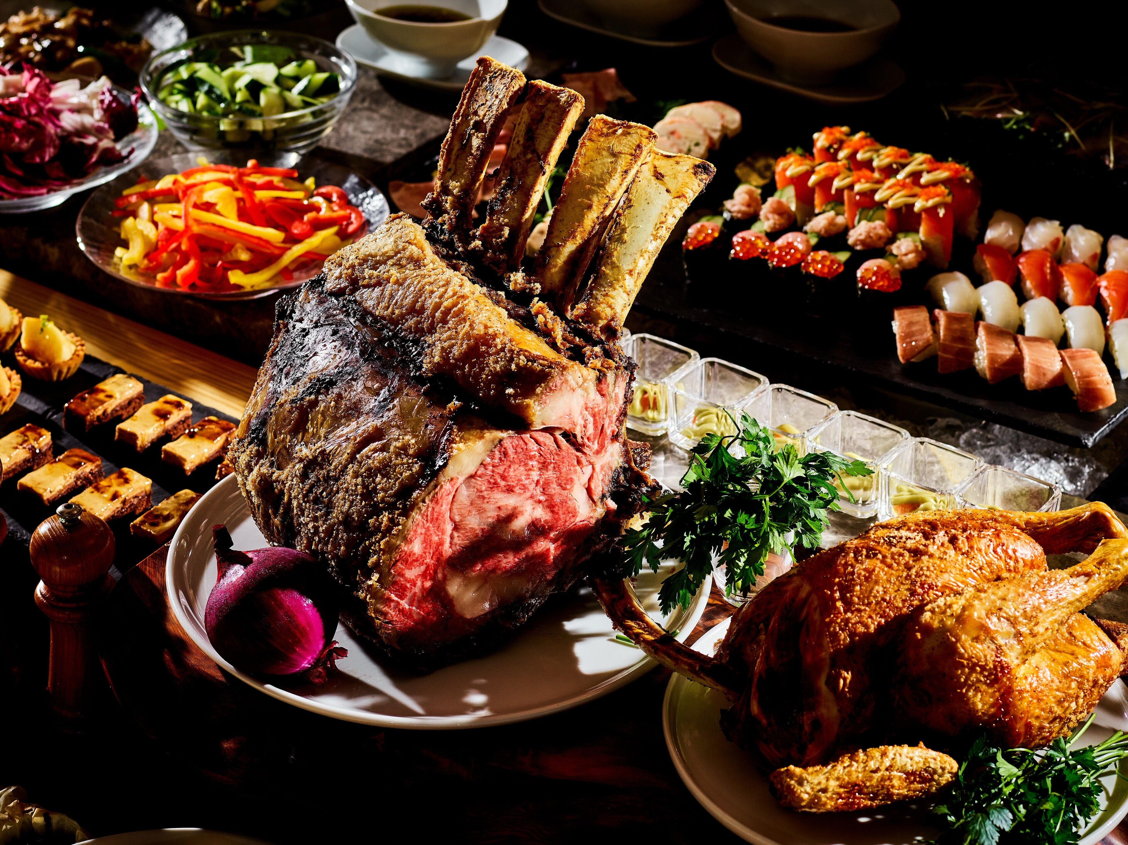 Una variedad de platillos, incluyendo carnes asadas, verduras y aperitivos, sobre una mesa.