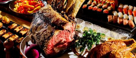 Una variedad de platillos, incluyendo carnes asadas, verduras y aperitivos, sobre una mesa.