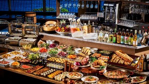 Un buffet proposant une variété de plats et de boissons, ainsi qu’un bar avec des bouteilles et des verres.