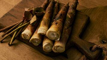 A wooden cutting board with several root vegetables and herbs on it.