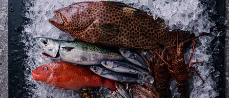 A variety of seafood on ice, including fish and a lobster.