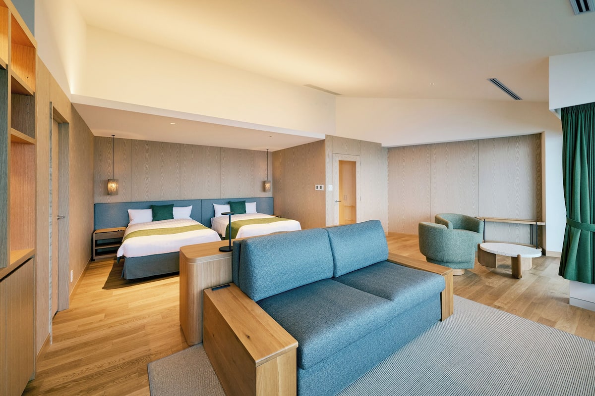 Een moderne hotelkamer met een groot bed, een slaapbank, een tafeltje en een bureau.
