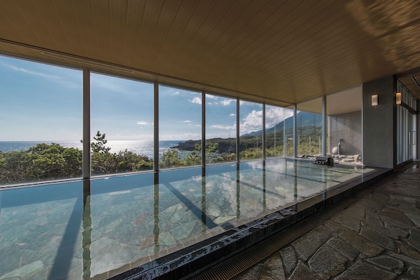 Una piscina infinita moderna con paredes de vidrio transparente, que ofrece vistas al océano y al paisaje circundante.