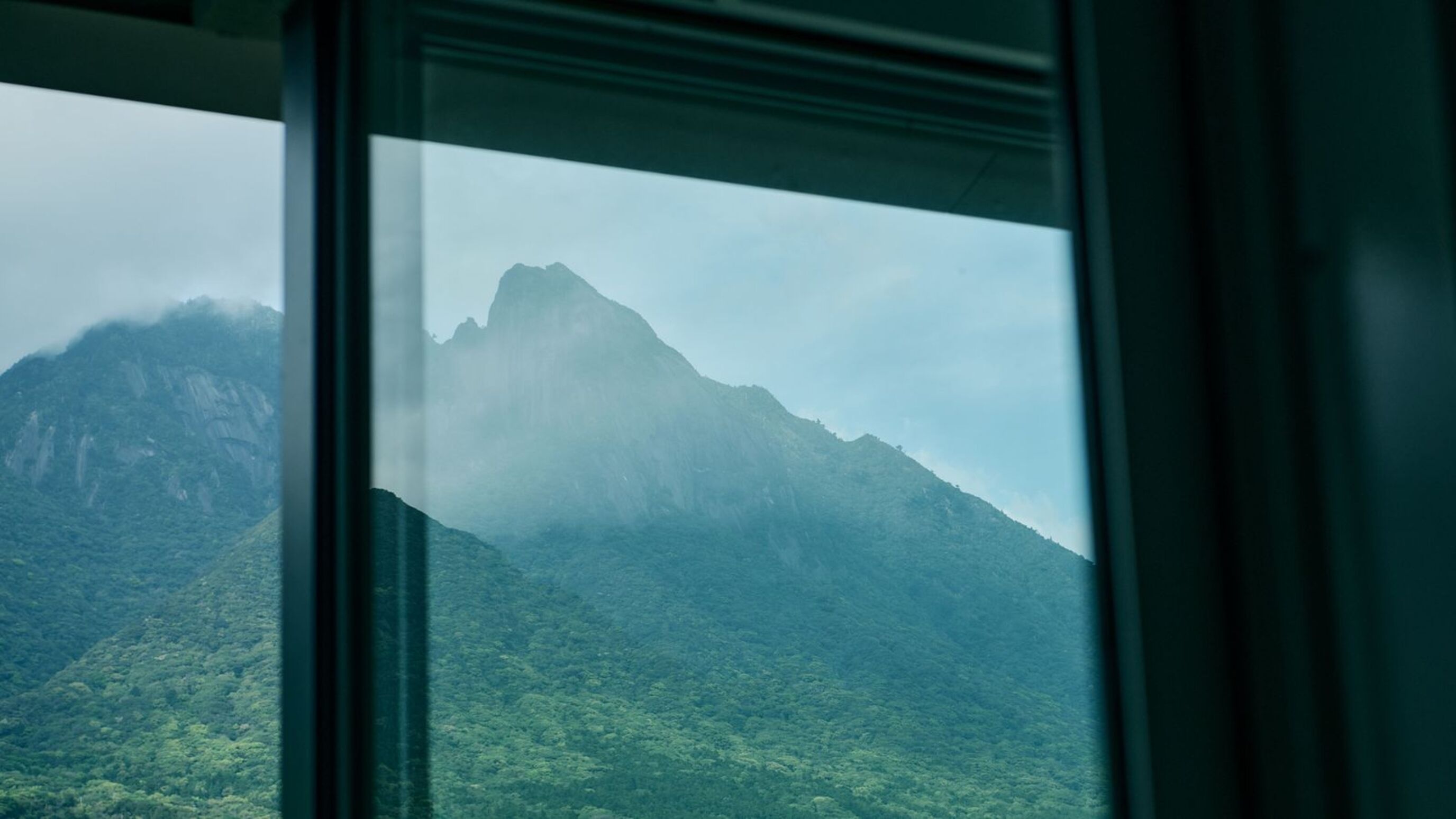 A mountain view through a window with a clear sky.