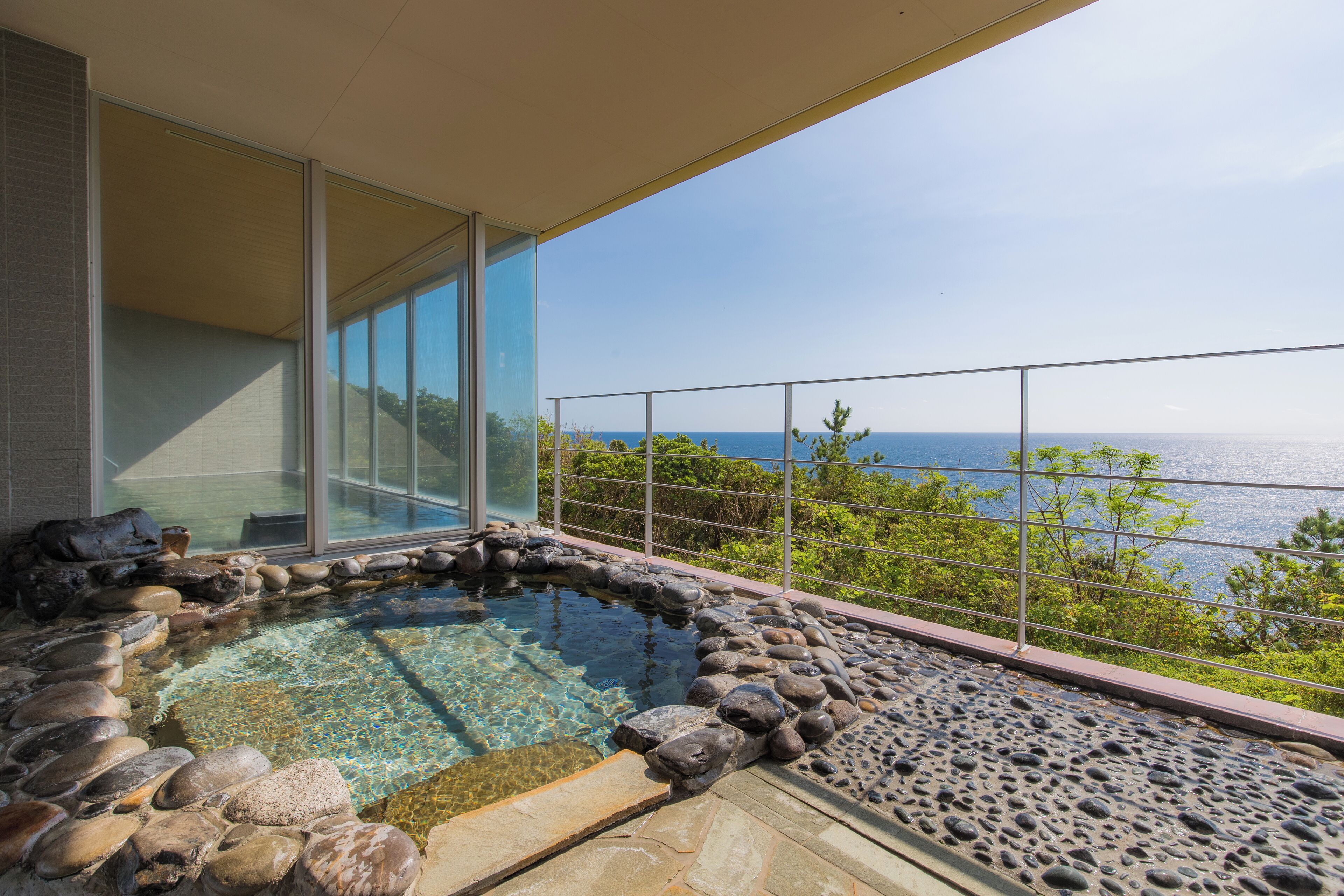 A hot tub with a stone border and a view of the sea.