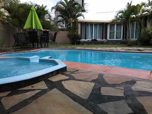 A swimming pool with a hot tub, surrounded by stone tiles and outdoor furniture. - H&K Villa (Blue Bay)
