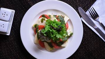 A white plate with a salad on a dark woven tablecloth.