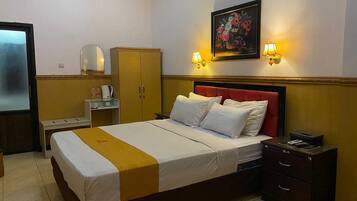 Una habitación de hotel con una cama, mesitas de noche, un armario y un cuadro colgado en la pared.