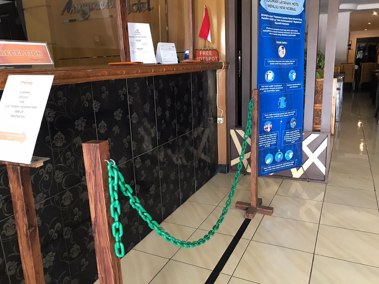 Zona de recepción con mostrador, señal que indica un espacio disponible y un cartel informativo azul.
