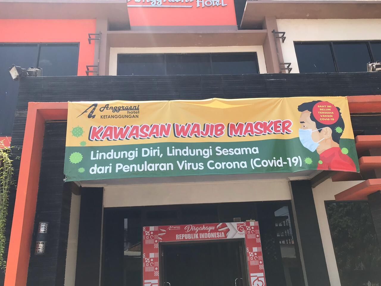 A hotel entrance with a banner advertising free masks and health checks for COVID-19.