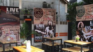 An outdoor seating area with wooden tables and chairs, surrounded by walls adorned with 'Live Music' and 'Terrace Cafe' posters. - Anggraeni Hotel Ketanggungan (Ketanggungan)