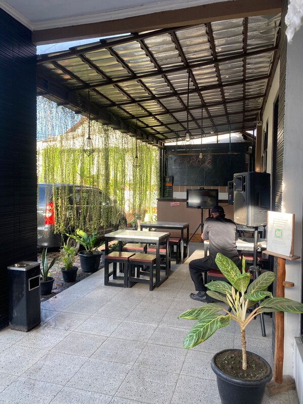 An outdoor patio with a metal roof, tables, chairs, and potted plants.