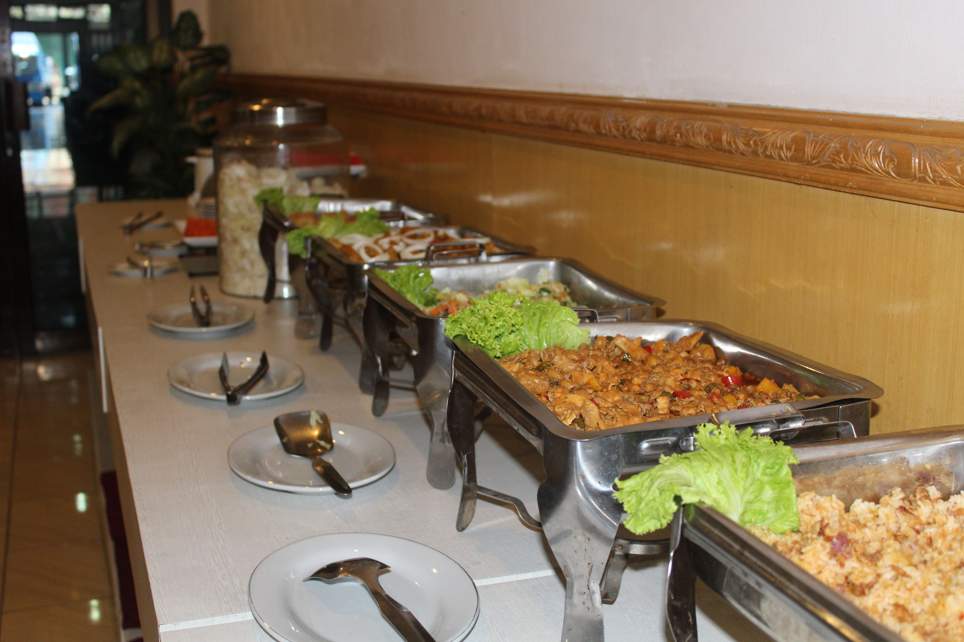 Una barra de buffet con diversos platos, entre ellos ensaladas y arroz, en un ambiente de hotel.