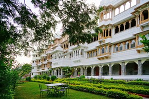 A traditional building with multiple balconies, a courtyard with seating, and lush greenery. - Kavish The Haveli Resort (Kumbhalgarh)