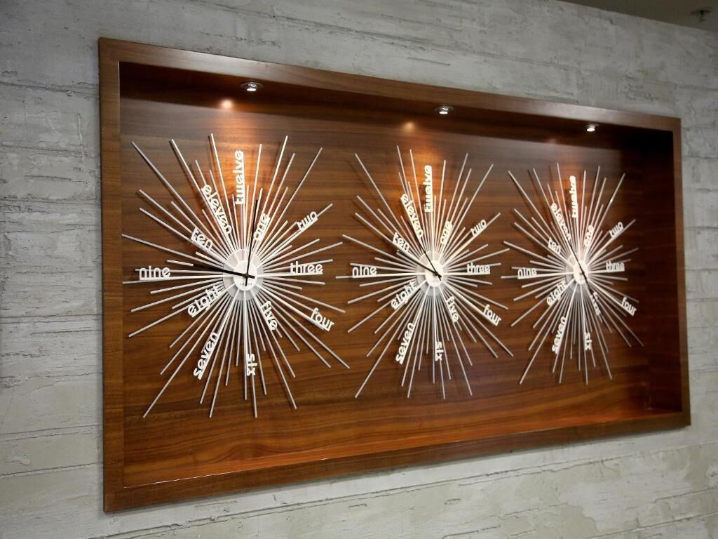 A wall-mounted clock with multiple time zones displayed in a radial design.