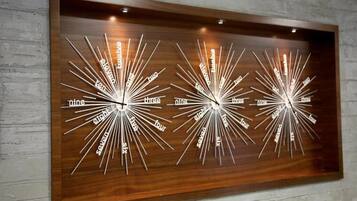 A wall-mounted clock with multiple time zones displayed in a radial design.