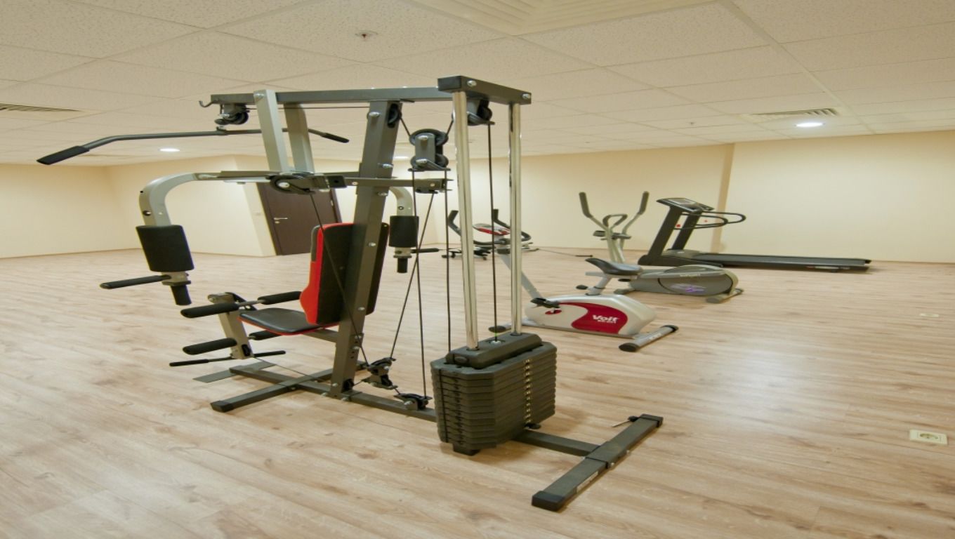 A gym with a variety of exercise equipment including a weight machine, a stair climber, and an elliptical trainer.
