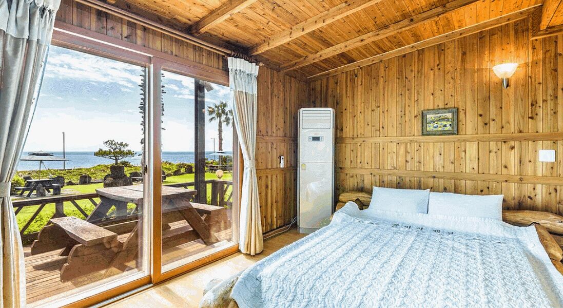 Une pièce en bois avec un lit, un radiateur et une vue sur l’extérieur.