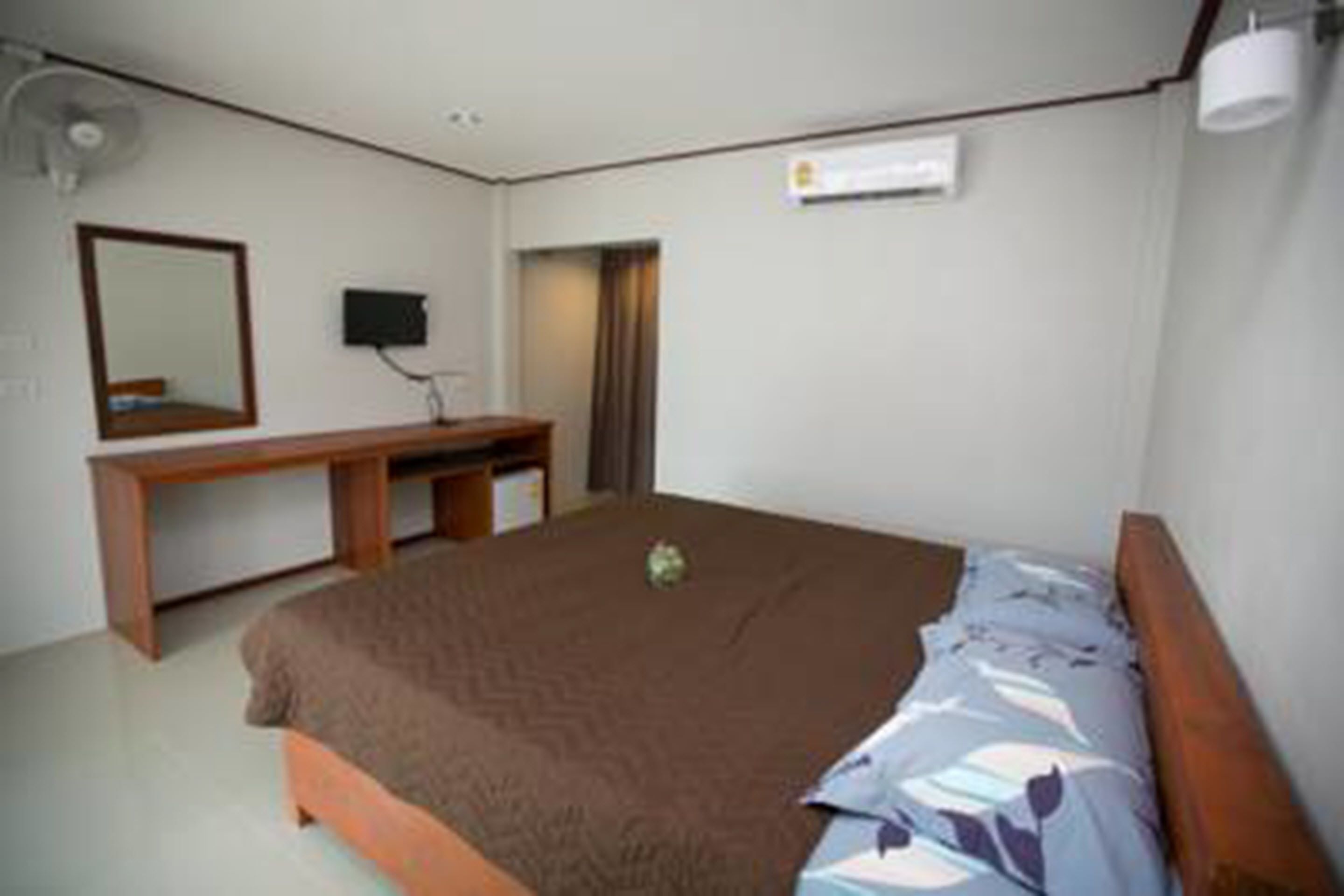 Un dormitorio con cama, escritorio, silla, espejo y aire acondicionado instalado en la pared.