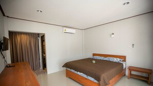 A bedroom with a wooden bed, a bedside table, a desk, and an air conditioning unit. - Lamai Resort (Koh Samui)
