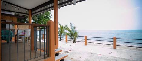 Une propriété située en bord de mer, dotée d’un espace extérieur couvert avec des sièges et offrant une vue sur l’océan.