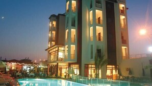 Ein mehrstöckiges Hotel mit Schwimmbad, Balkonen und einer Bar.