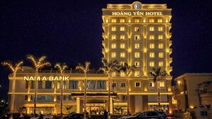 Un hôtel avec une enseigne bien visible portant l’inscription « HÔTEL HOÀNG YÊN » et une banque nommée « BANQUE NAM A » située en face.