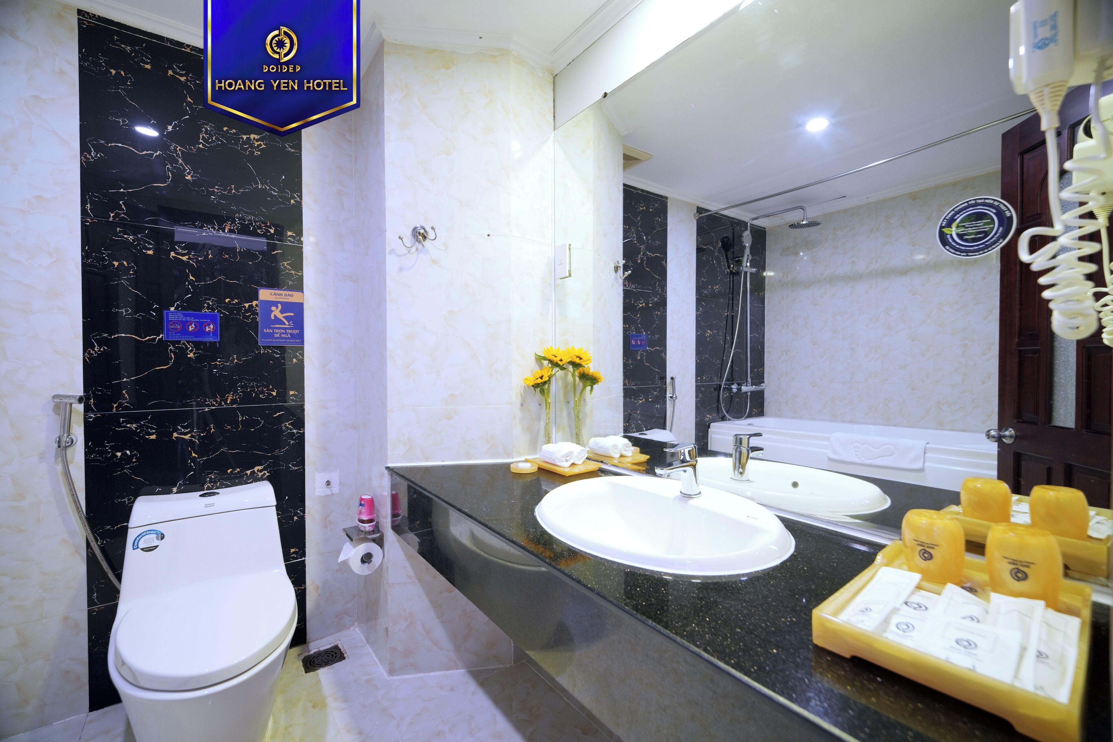 Un baño con inodoro, lavabo y ducha. Hay artículos de aseo en la encimera.