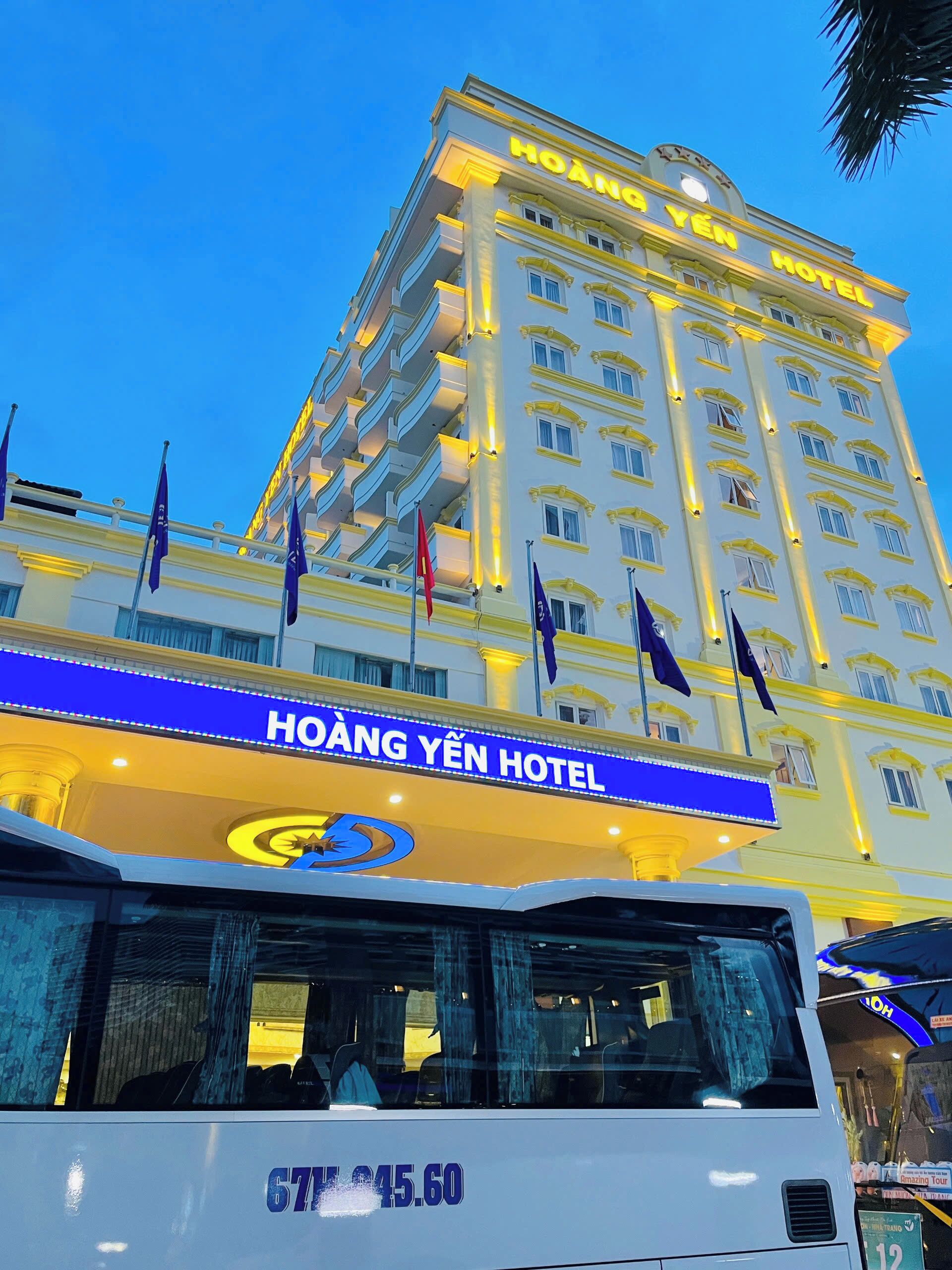 A hotel building with a sign reading 'HOANG YEN HOTEL' and a bus in front.