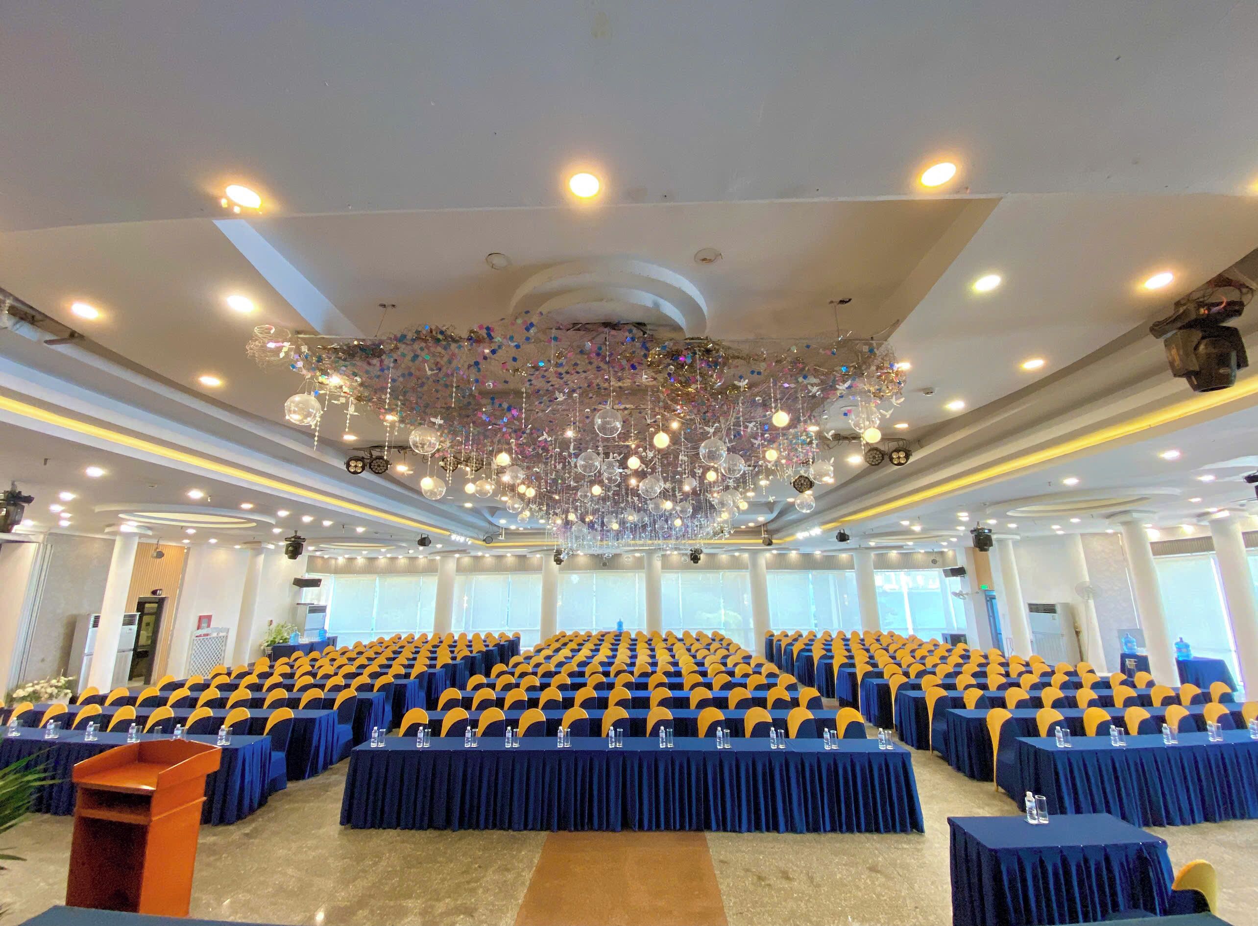 A conference room with rows of tables, a podium, and a decorative ceiling.