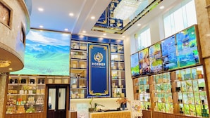 Un hall d’hôtel doté d’un grand écran numérique, d’un comptoir d’accueil et d’une présentation de divers objets.