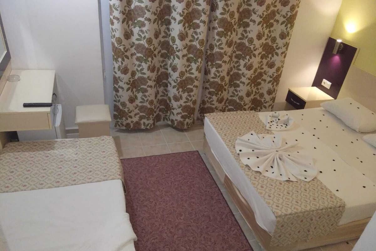 A hotel room with two beds, a desk, a chair, a small table, and a nightstand.