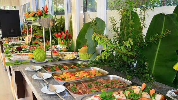 Tarjolla on runsas buffet, jossa on erilaisia ruokia, kuten riisiä, kasviksia ja lihaa, ja ne on aseteltu kauniisti marmoritasolle.