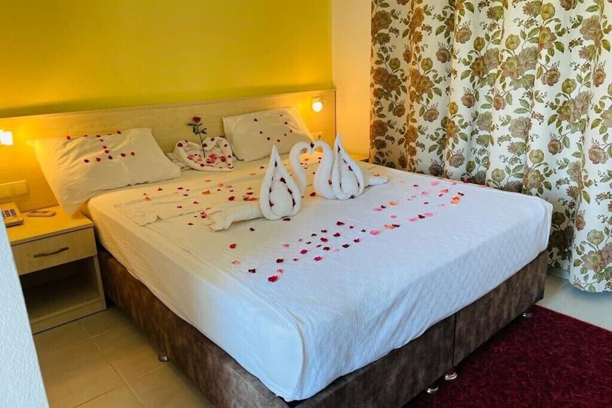 A neatly made bed with a white duvet, pillows, and a floral curtain.
