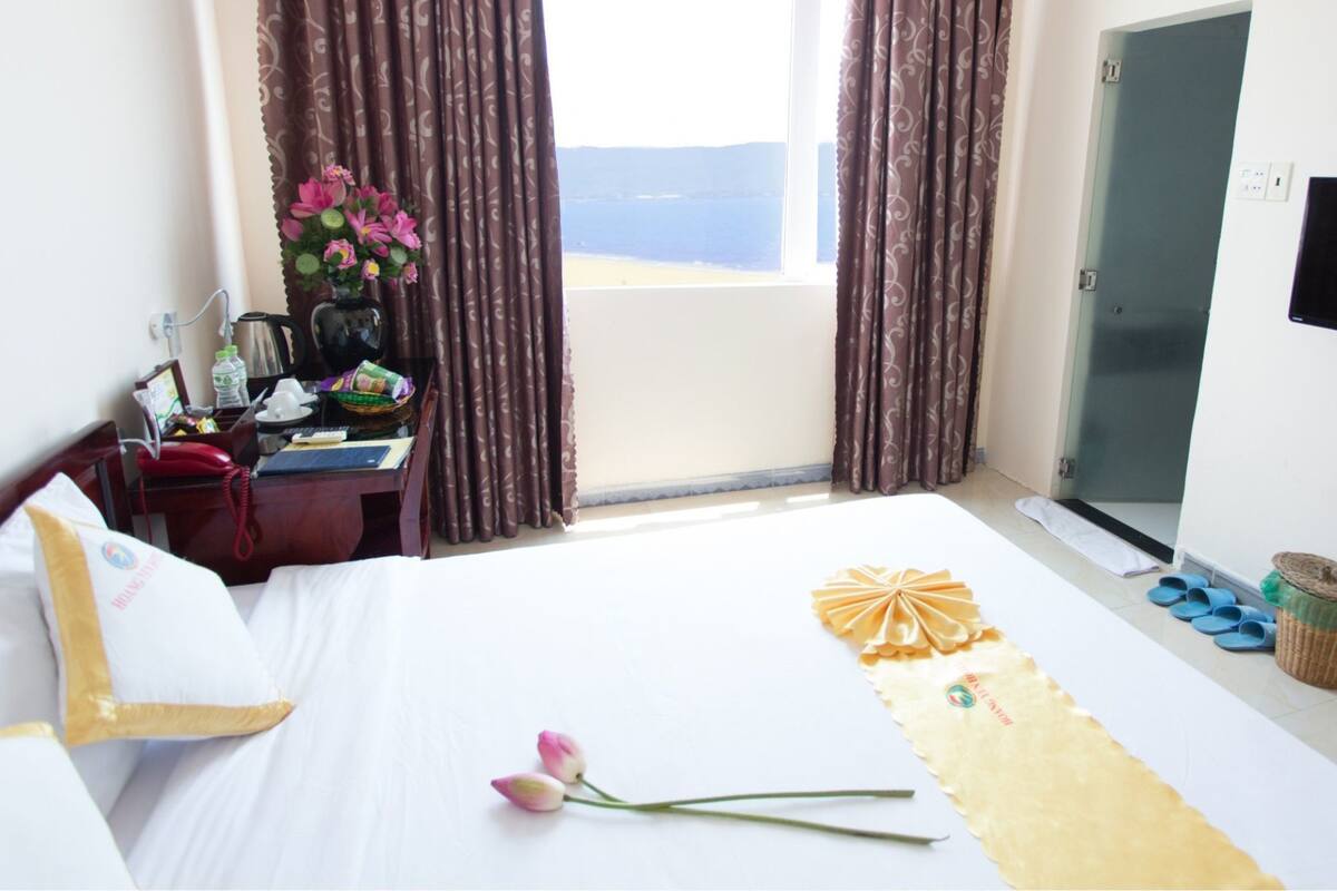 Ein Hotelzimmer mit Bett, Schreibtisch mit Computer, Wand-Fernseher und einem Fenster mit Vorhängen.