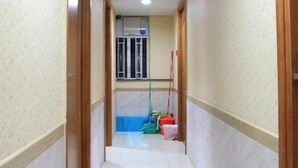 A narrow hallway with tiled floors, wooden doors, and a window with blinds. - Lung Wa Hotel (Kowloon)