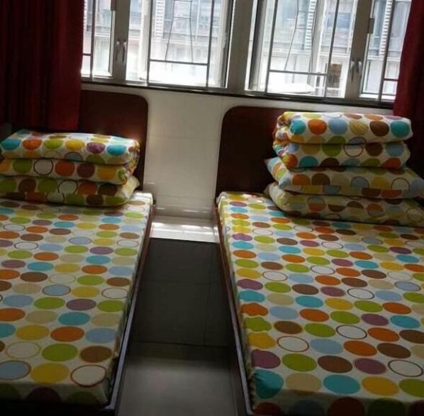 Una habitación con dos camas, cada una con una alegre colcha de lunares.