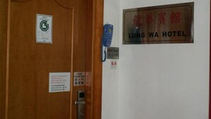 A hotel entrance with a wooden door, a sign for Lung Wa Hotel, and a blue telephone. - Lung Wa Hotel (Kowloon)