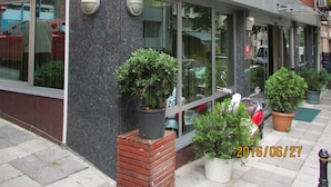 A building with a sign that reads "KADIKOY OTEL KONAK LTD. STI". There are potted plants outside and a scooter parked in front.