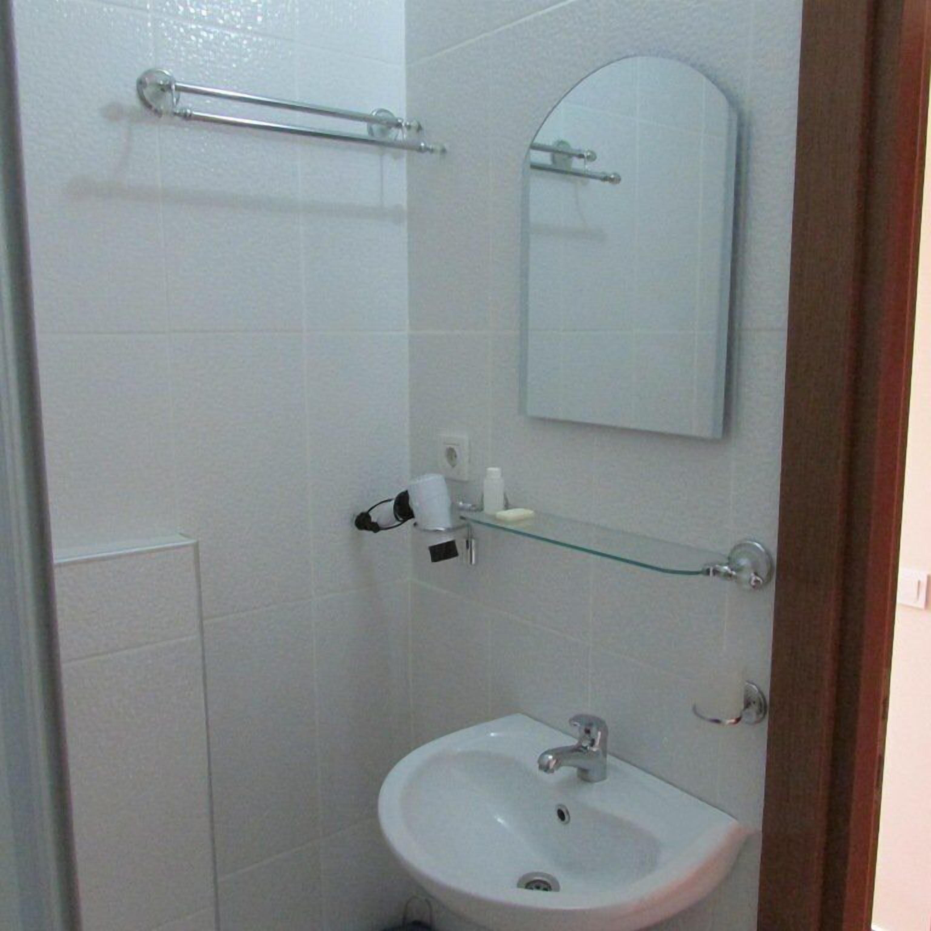 Un baño pequeño con un lavamanos blanco, un espejo y un estante de vidrio.