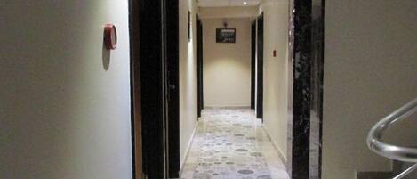 A hallway with patterned flooring, doors on both sides, and a staircase on the right.