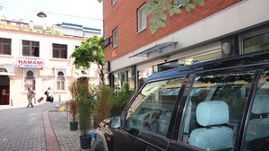 Un coche negro estacionado en una calle adoquinada frente a un edificio con un letrero que dice "HAMAMI TURKISH BATH".