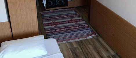 Habitación de hotel con cama, escritorio, silla, armario, un cuadro y una alfombra.