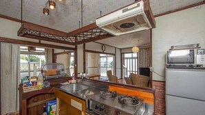 A kitchen with a stove, microwave, and refrigerator. - Pension Coral (Nakijin)