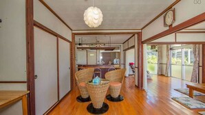 A traditional Japanese-style interior with tatami flooring, a low table with cushions, and a hanging light fixture. - Pension Coral (Nakijin)