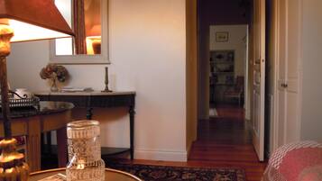 A cozy room with a wooden desk, a lamp, a vase with flowers, and a bookshelf in the background.