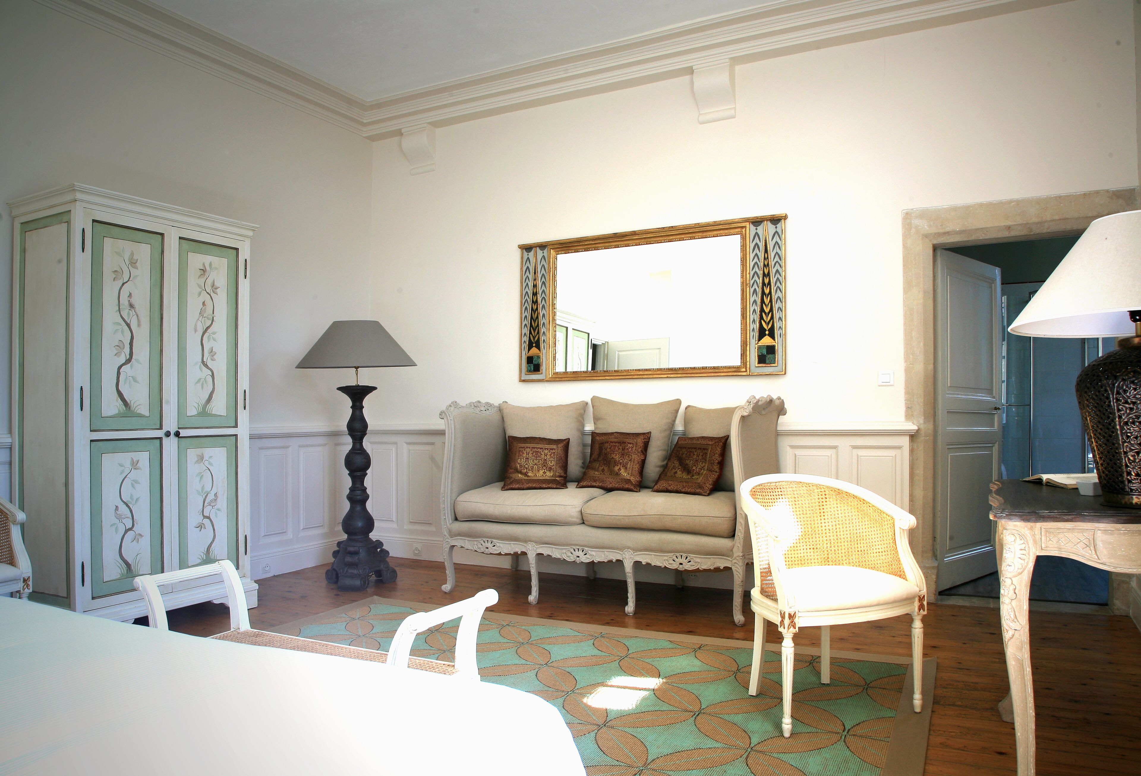 Une pièce comprenant un canapé, deux fauteuils, une table, une lampe et un miroir.