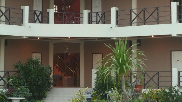 A two-story building with a balcony, potted plants, and a staircase leading to the upper level. - Baan Chomphu (Prachuap Khiri Khan)