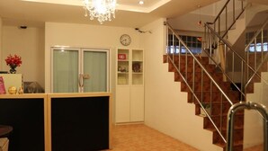 A modern interior with a staircase, a chandelier, a clock, and a cabinet. - Baan Chomphu (Prachuap Khiri Khan)