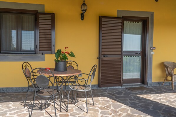 A patio with a round table and metal chairs, a potted plant, and a door with a window.